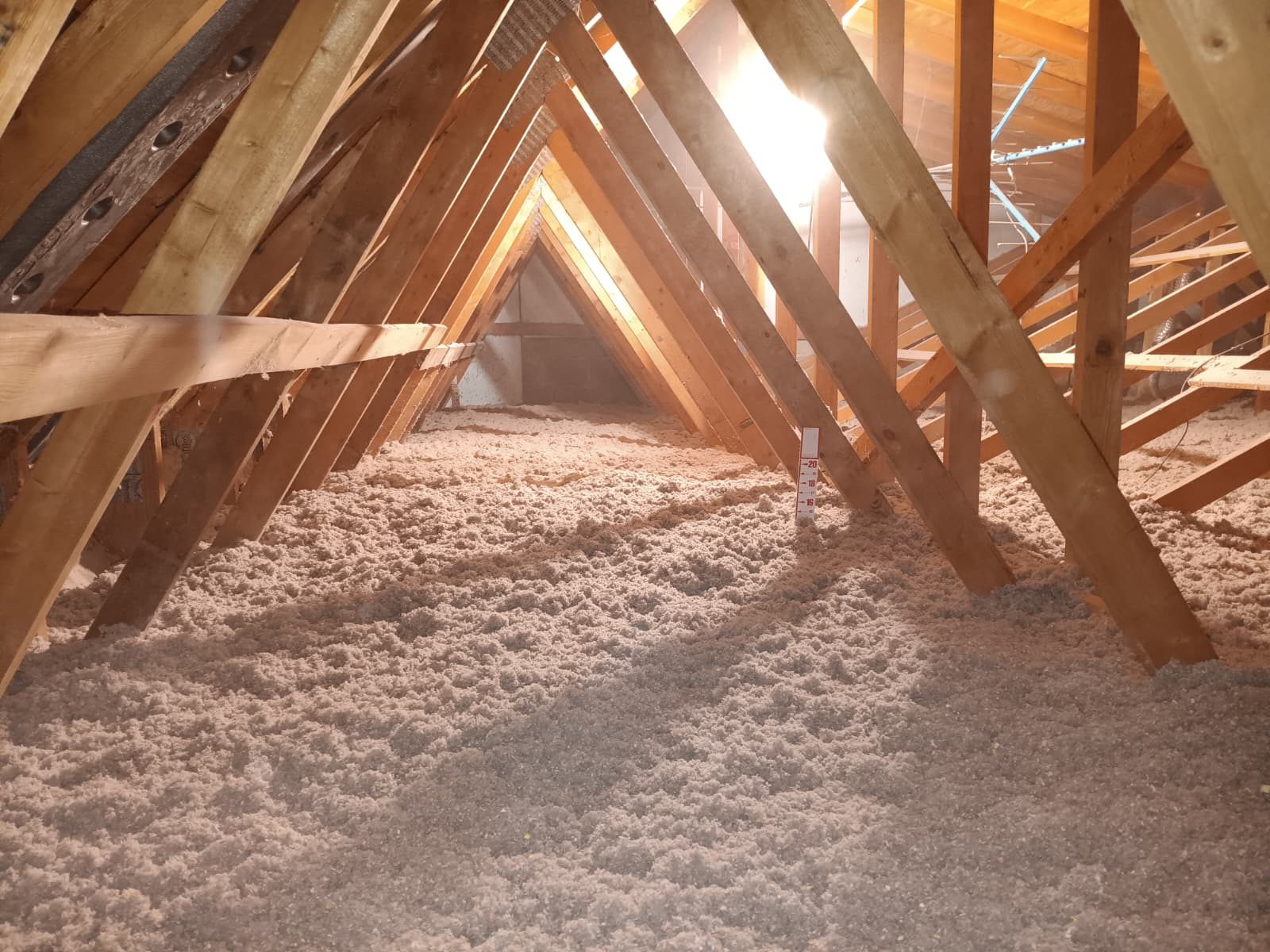 Even blanket of blown-in cellulose insulation covering an attic floor between rafters