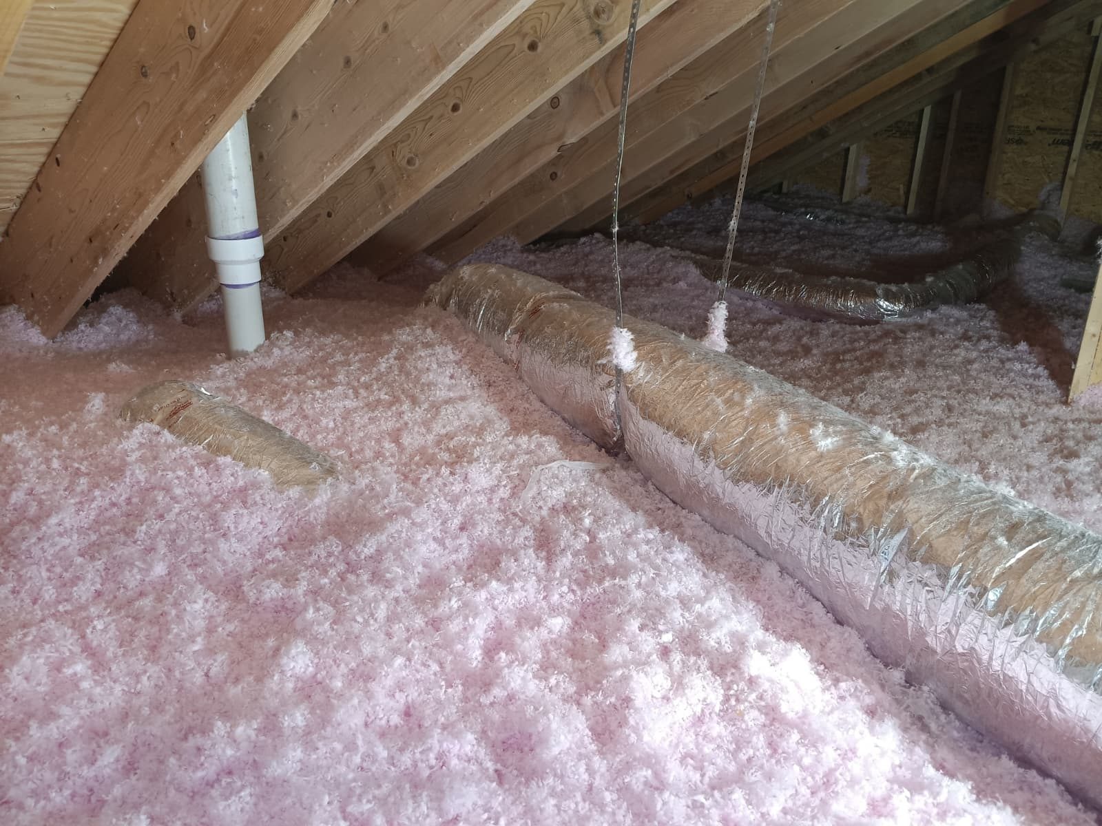 Blown insulation covering an attic floor around insulated ductwork