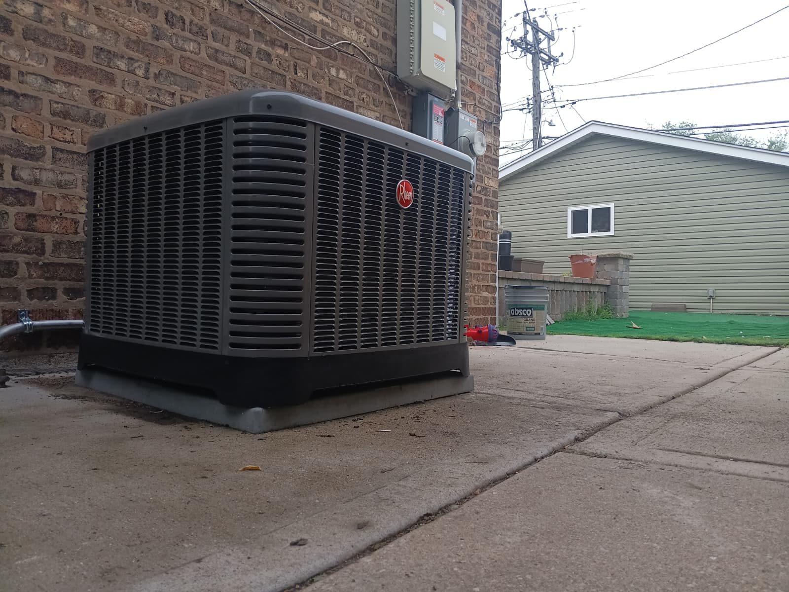 Newly installed Rheem outdoor condenser unit on a concrete pad behind a Chicago home