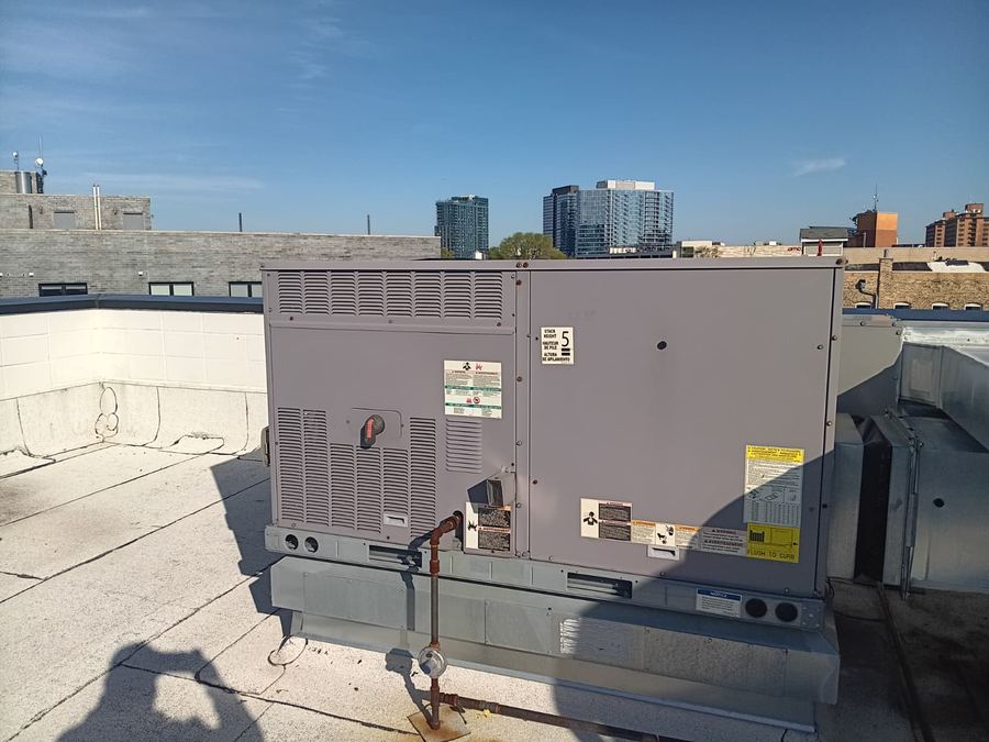 Commercial rooftop packaged HVAC unit installed on a curb with the skyline behind