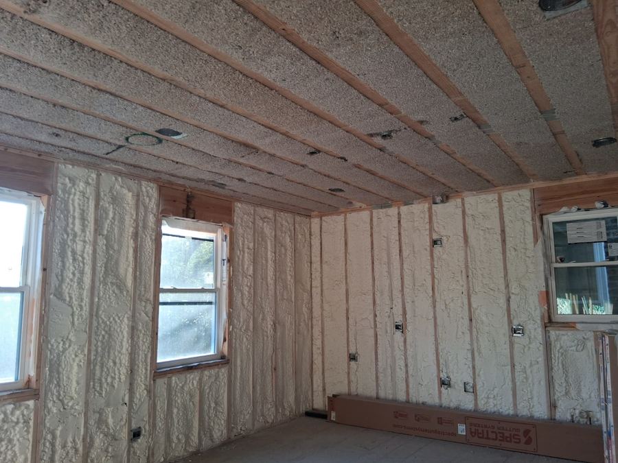 Spray foam insulation applied between wall studs and ceiling joists in a gutted room